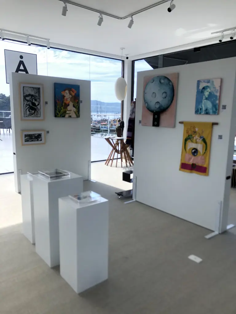 Obras da exposição Múltiplos Territórios na AGaleria Ubatuba, com diferentes linguagens artísticas e vista para a marina do Saco da Ribeira.