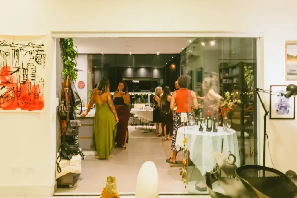 Convidados reunidos em uma experiência de arte da AGaleria em Casa, com obras expostas no ambiente.