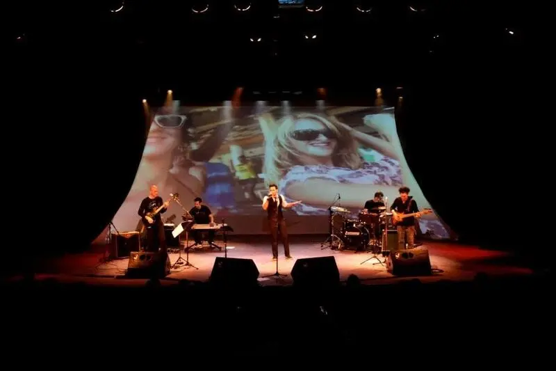Pedro Lobo e músicos durante apresentação com projeção audiovisual ao fundo.